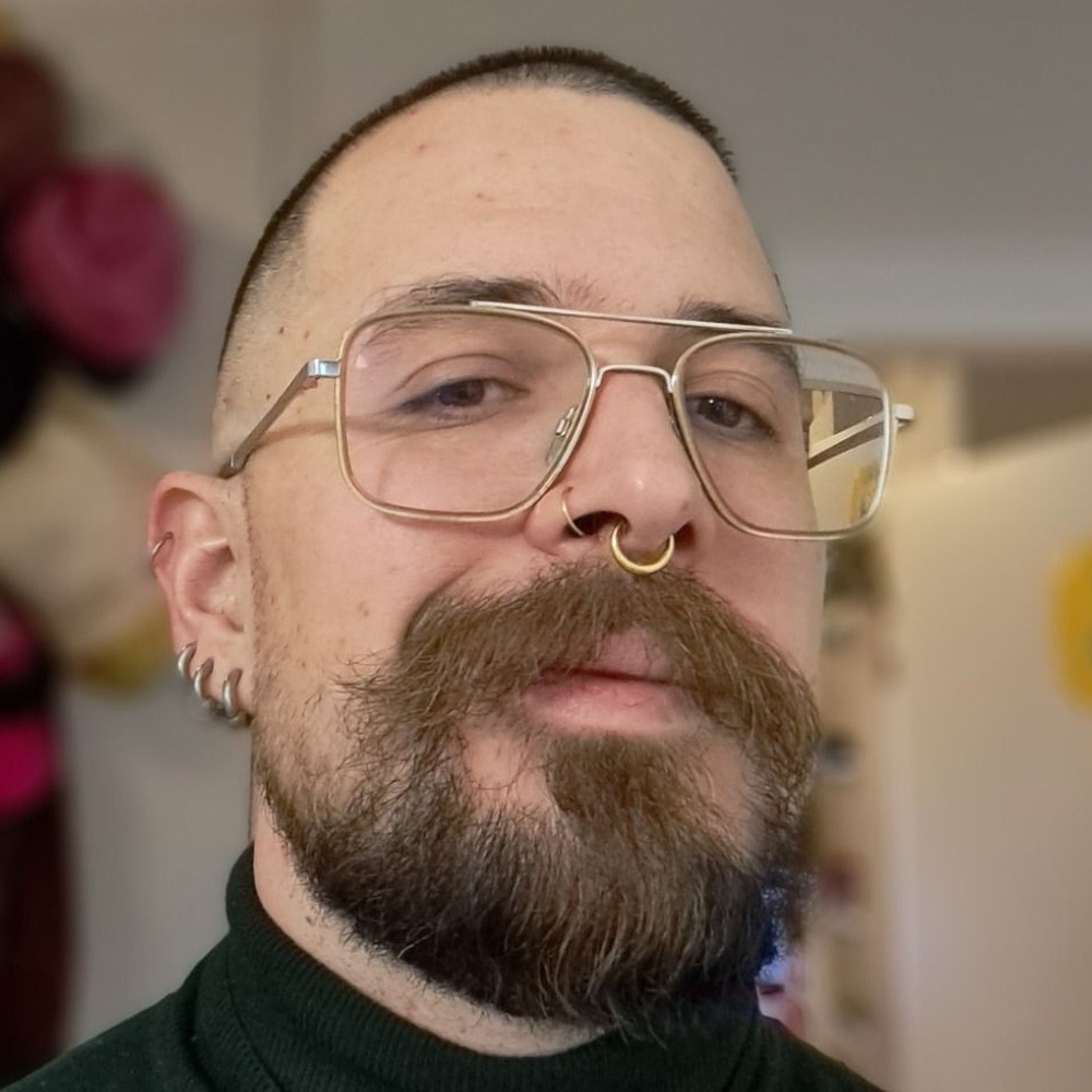 Louis Huppenbauer, looking directly at the camera, wearing wire-frame glasses and a septum ring.